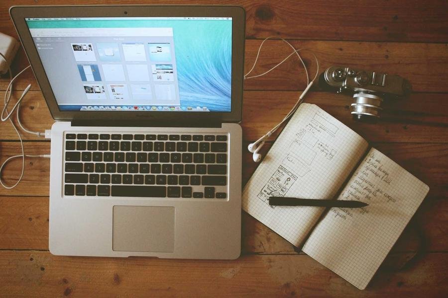 Laptop, notebook and camera on wooden desk | Techyza WordPress Development Agency
